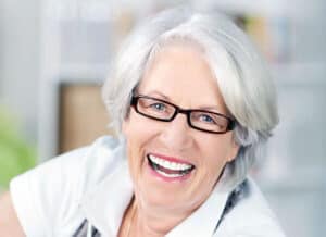 A smiling older woman with glasses, healthcare provider at Tower Urology clinic.